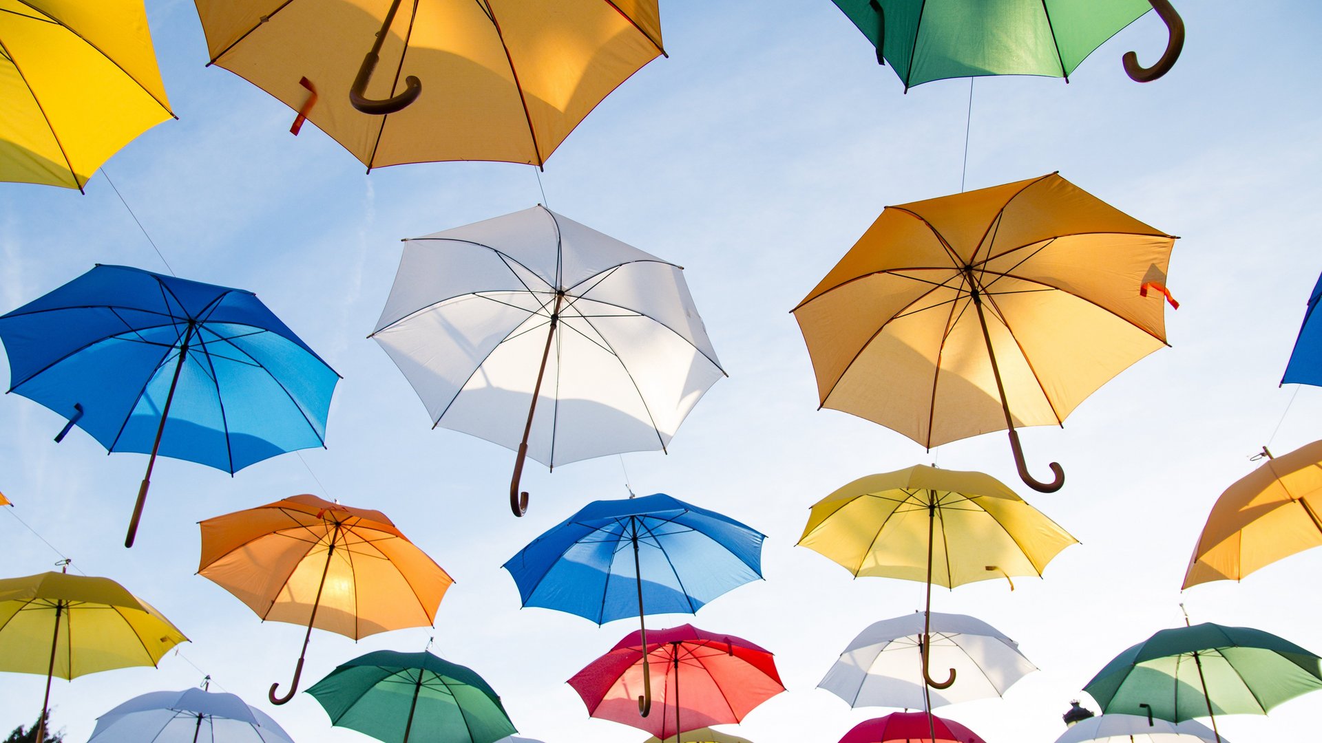 Bunte Regenschirme die unter blauem Himmel hängen