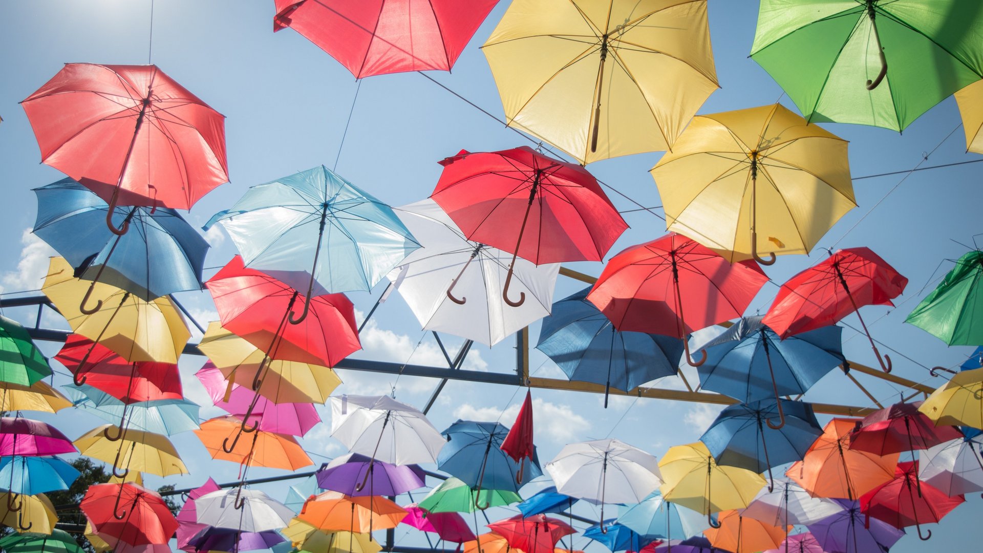 Bunte Regenschirme die unter blauem Himmel hängen